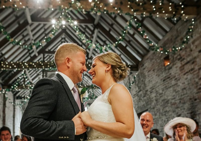 newlyweds embrace under lights in barn