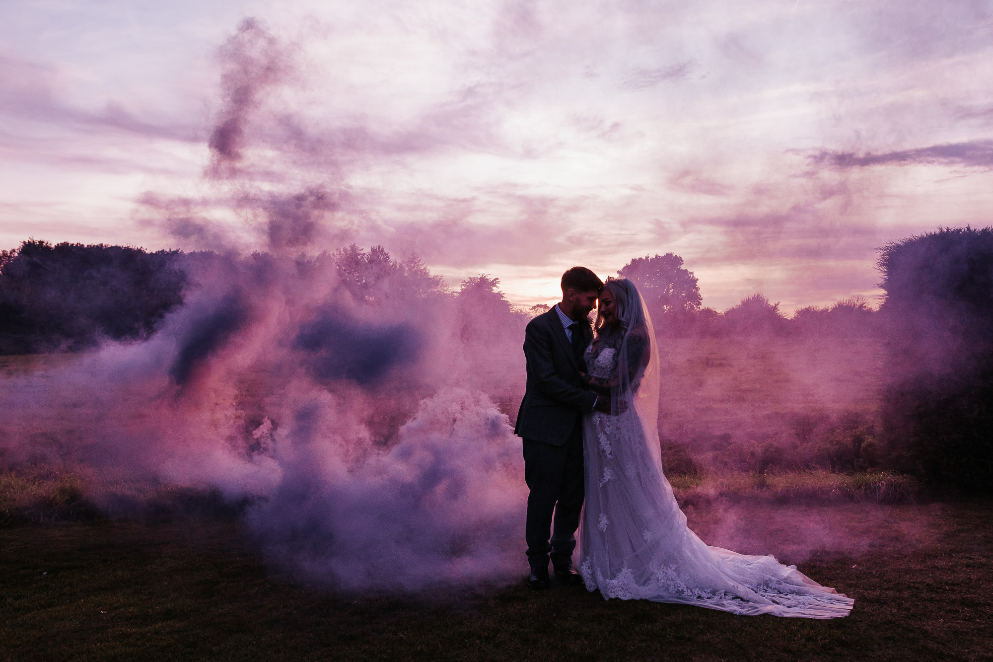 couple stands in purple smoke