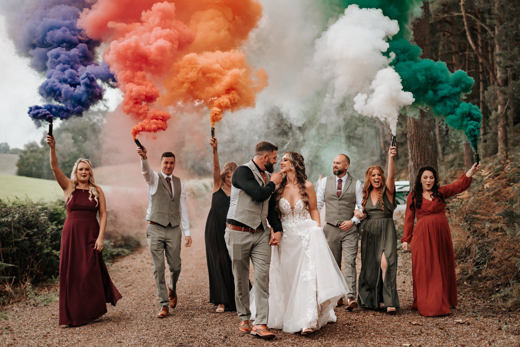 friends walk through forest holding coloured smoke 